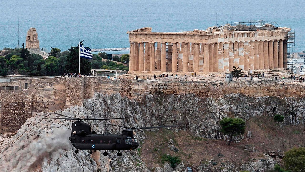 Un helicóptero de la Fuerza Aérea Helénica sobrevuela el Templo del Partenón en la cima de la colina de la Acrópolis en Atenas, durante las celebraciones del Día Nacional  | Foto:Angelos Tzortzinis / AFP