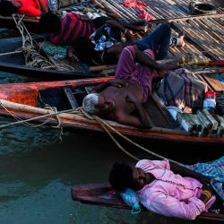 Los pescadores duermen una siesta en los barcos amarrados a lo largo del río Ganges mientras esperan que la marea alta comience a pescar, en Calcuta. | Foto:Dibyangshu Sarkar / AFP