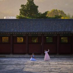 Los visitantes con un vestido tradicional hanbok coreano posan para fotos en el palacio Gyeongbokgung en Seúl. | Foto:Ed Jones / AFP
