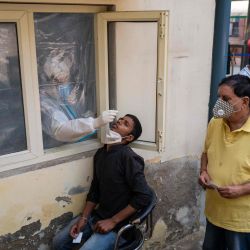 Un trabajador médico recolecta una muestra de hisopo de un hombre en un sitio de detección de coronavirus Covid-19 en Nueva Delhi. | Foto:Jewel Samad / AFP