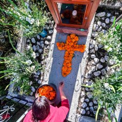 Una mujer decora la tumba de un familiar con caléndulas mexicanas formando una cruz en el Panteón La Magdalena, en San Pedro Cholula, estado de Puebla, México, en el Día de Todos los Santos, en medio de la pandemia del coronavirus COVID-19. | Foto:Pedro Pardo / AFP
