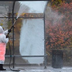 Un trabajador municipal con equipo de protección rocía desinfectante en una parada de autobús en Moscú, en medio de la pandemia de coronavirus en curso. | Foto:Natalia Kolesnikova / AFP