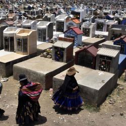 Mujeres indígenas caminan junto a las tumbas del cementerio Mercedario en El Alto, Bolivia, durante la conmemoración del Día de Muertos. | Foto:Aizar Raldes / AFP