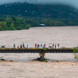 La gente observa la inundación del río Humuya debido a las fuertes lluvias causadas por el huracán Eta, en Santa Rita, departamento de Yoro, 240 km al norte de Tegucigalpa. | Foto:Orlando Sierra / AFP
