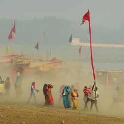 Los devotos hindúes llevan una bandera religiosa mientras caminan en medio del polvo a través de Sangam, la confluencia de los ríos Ganges, Yamuna y el mítico Saraswati, en Allahabad. | Foto:Sanjay Kanojia / AFP