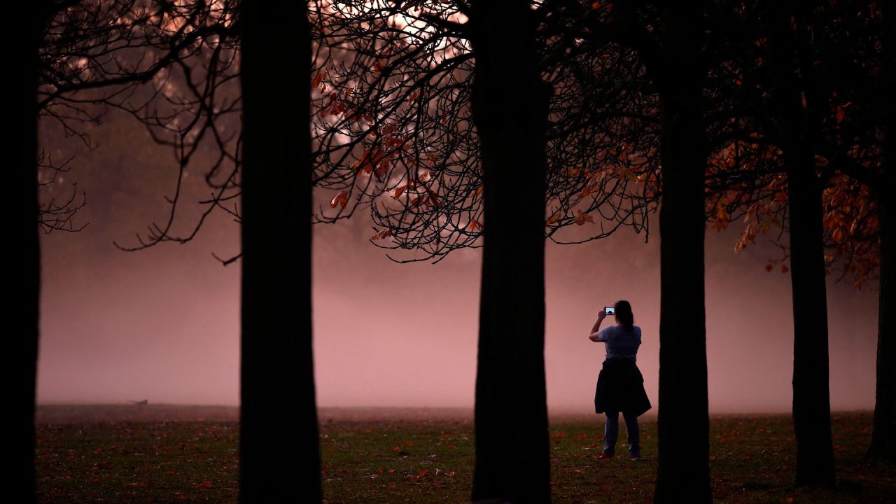Una persona toma una fotografía de la niebla de la mañana al amanecer en Greenwich Park en el sur de Londres. | Foto:DANIEL LEAL-OLIVAS / AFP