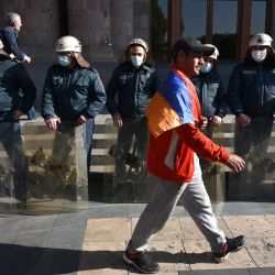 Un hombre pasa junto a los agentes de policía armenios que protegen el edificio del gobierno después de protestar contra el acuerdo del país para poner fin a los enfrentamientos con Azerbaiyán por la disputada región de Nagorno-Karabaj frente a la sede del gobierno en Ereván. | Foto:Karen Minasyan / AFP