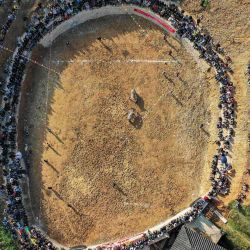 Esta foto aérea muestra a personas del grupo étnico Miao viendo una corrida de toros durante una ceremonia anual del festival  | Foto:STR / AFP