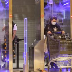 Los clientes caminan a través de un 'túnel de desinfección' empujando carritos de la compra al entrar en el supermercado Leclerc Baleone en Ajaccio en la isla mediterránea francesa de Córcega. | Foto:PASCAL POCHARD-CASABIANCA / AFP