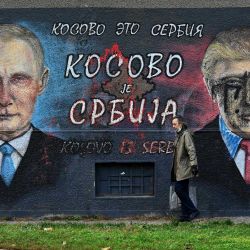 Un peatón pasa junto a un mural que representa al presidente ruso Vladimir Putin Y al presidente estadounidense Donald Trump y que lleva una escritura cirílica que dice  | Foto:Andrej Isakovic / AFP