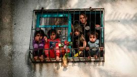 Los niños miran desde una ventana mientras los militantes palestinos de la Jihad Islámica participan en un mitin militar en la ciudad de Gaza para conmemorar el primer aniversario del asesinato del comandante del grupo, Baha Abu Al-Ata, en un ataque a su casa en el Franja de Gaza.