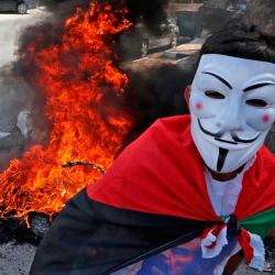 Un hombre que lleva una máscara de Guy Falkes aparece mientras los partidarios del movimiento palestino Fatah marchan para conmemorar el 16 aniversario de su muerte en la aldea de Dura, cerca de la ciudad cisjordana de Hebrón. | Foto:Hazem Bader / AFP