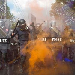 El humo naranja de una granada de humo envuelve a una fila de policías que intentan dispersar a los manifestantes a favor de la democracia durante una manifestación antigubernamental cerca del Parlamento tailandés en Bangkok. | Foto:Cory Wright / AFP