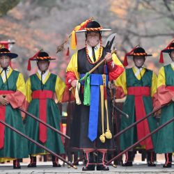 Los miembros de la 'guardia del palacio' con máscaras faciales participan en una ceremonia de 'cambio de guardia' para turistas en la puerta principal del Palacio Deoksugung en Seúl. | Foto:Jung Yeon-je / AFP