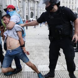 Police detain a man during clashes while fans wait to enter the Government House to pay tribute to late football legend Diego Armando Maradona in Buenos Aires, on November 26, 2020.