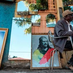 Un hombre sentado frente a una tienda que vende espejos y pinturas en Gondar, Etiopía. | Foto:Eduardo Soteras / AFP