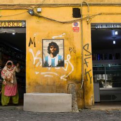 Una mujer barre junto a un mural dedicado a Diego Armando Maradona, del artista callejero Harry Greb se ve en el barrio de Trastevere de Roma. | Foto:Alberto Pizzoli / AFP