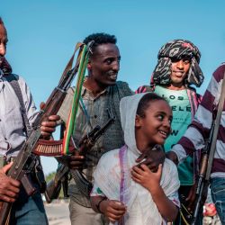 Una joven posa para una fotografía con miembros de la milicia Amhara en una calle de Mai Kadra, Etiopía. | Foto:Eduardo Soteras / AFP