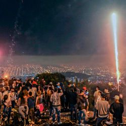 La gente mira los fuegos artificiales durante la Alborada, una tradición para celebrar la llegada de la temporada navideña, en Medellín, Colombia, en medio de la pandemia del nuevo coronavirus COVID-19. | Foto:Joaquín Sarmiento / AFP