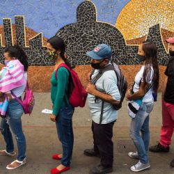 La gente hace fila para abordar un autobús junto a un mural que representa el edificio de la Asamblea Nacional, en Caracas antes de las elecciones parlamentarias en el país. | Foto:Cristian Hernandez / AFP