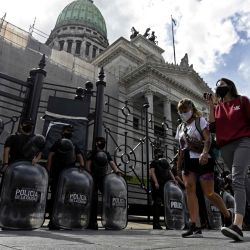 Las mujeres pasan junto a una fila de policías antidisturbios que hacen guardia frente al edificio del Congreso en Buenos Aires, donde las comisiones discuten un proyecto de ley para legalizar el aborto que se votará en la cámara baja la próxima semana. | Foto:Juan Mabromata / AFP