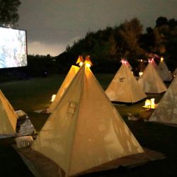 Líneas de carpas estilo tipi se colocan en el césped frente a una pantalla grande en 'Cinema Under the Stars', un nuevo espacio de cine al aire libre al estilo de un campamento con el objetivo de mantener a las personas entretenidas y socialmente distanciadas en medio de la pandemia del coronavirus Covid-19. en Bandung. | Foto:Timur Matahari / AFP