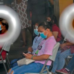 La gente espera a que le recojan una muestra de hisopo para realizar una prueba de COVID-19 en el distrito de San Miguelito, en la ciudad de Panamá. | Foto:STR / AFP