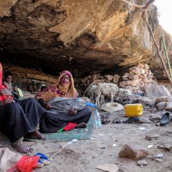 Mujeres y niños se sientan en el suelo en una choza junto a una cueva donde una familia yemení ha buscado refugio debido a la pobreza y la falta de vivienda, al oeste de los suburbios de la tercera ciudad de Taez en Yemen. | Foto:AHMAD AL -BASHA / AFP