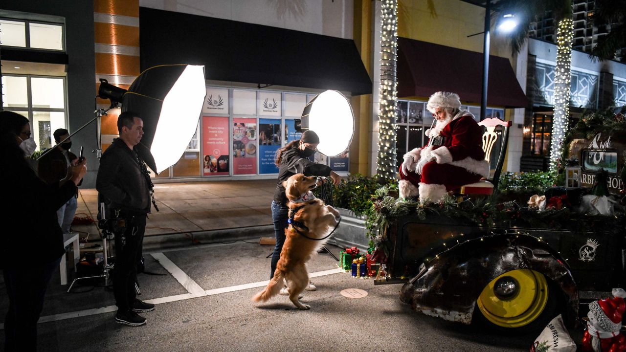 Una mujer y su perro posan para una foto con Santa Claus en un centro comercial en Miami. | Foto:Chandan Khanna / AFP