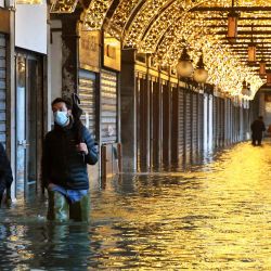 La gente camina a través de una galería junto a una Plaza de San Marcos inundada en Venecia luego de un evento de marea alta  | Foto:ANDREA PATTARO / AFP
