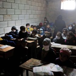 Niños de la escuela sirios con máscaras debido a la pandemia Covid-19, se sientan en una escuela improvisada establecida por los lugareños en la aldea de Ma'arin en las afueras de Azaz en el campo norte controlado por los rebeldes de la provincia de Alepo en Siria. | Foto:AAREF WATAD / AFP
