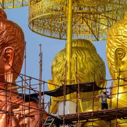 Un trabajador camina a lo largo de un andamio que rodea tres estatuas gigantes de Buda en un nuevo complejo religioso en Samut Prakan, a unos 25 km al sur de Bangkok. | Foto:Mladen Antonov / AFP