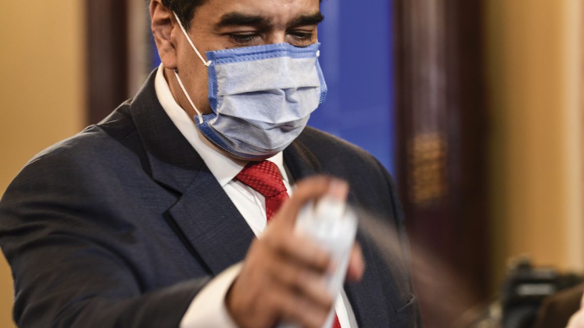 Venezuela’s President Nicolás Maduro sprays disinfectant over journalists’ microphones after one tested positive for Covid-19, during a press conference at the Miraflores Presidential Palace in Caracas, on December 8, 2020. 