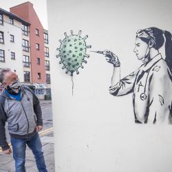 Escocia, Edimburgo: el público observa más de cerca una nueva obra de arte creada por el artista callejero The Rebel Bear en el centro de la ciudad de Edimburgo, que presenta a un médico administrando una inyección de vacuna en un globo con forma de coronavirus. | Foto:Jane Barlow / PA Wire / DPA