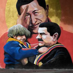Un hombre pasa junto a un mural que representa al difunto presidente venezolano Hugo Chávez y al presidente venezolano Nicolás Maduro sosteniendo a un niño en Caracas. | Foto:Federico Parra / AFP