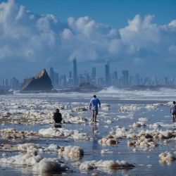 Los turistas caminan entre la espuma de la playa a raíz de las condiciones ciclónicas en la playa de Currumbin, después de que el clima salvaje azotara el norte de Nueva Gales del Sur y el sureste de Queensland de Australia con fuertes lluvias, vientos fuertes y mareas reales. | Foto:Patrick Hamilton / AFP