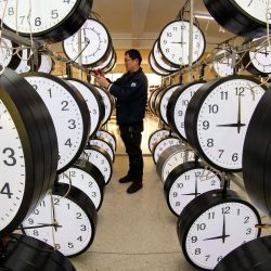 Un técnico revisa relojes colgantes en un taller de una empresa de relojes en Yantai, en la provincia de Shandong, en el este de China. | Foto:STR / AFP