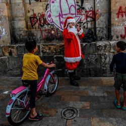 Niños migrantes venezolanos miran a un hombre vestido de Papá Noel en Bogotá. | Foto:Juan Barreto / AFP