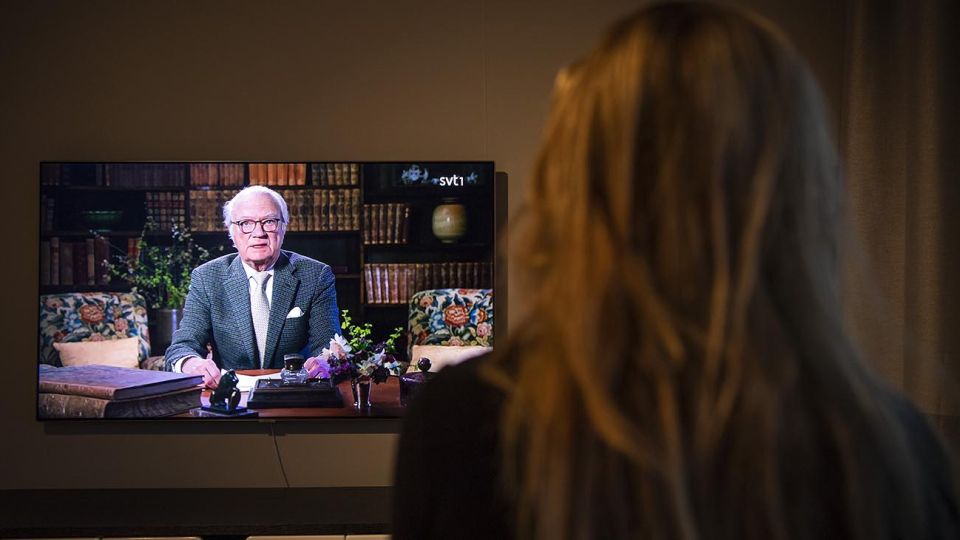En esta foto de archivo tomada el 5 de abril de 2020, una mujer observa al rey Carl XVI Gustaf de Suecia mientras se dirige a la nación sobre la nueva crisis del coronavirus COVID-19 transmitida por la televisión pública nacional sueca, SVT, en Sundbyberg, cerca de Estocolmo. El rey Carlos XVI Gustavo de Suecia dijo el 17 de diciembre de 2020 que el país
