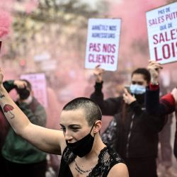Un manifestante sostiene una bengala junto a un cartel que dice  | Foto:Christophe Archambault / AFP