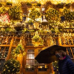 Inglaterra, Londres: una mujer que lleva una máscara facial pasa junto a las luces de Navidad frente al pub cerrado Churchill Arms en Kensington, al oeste de Londres, después de que la capital se moviera al nivel más alto de restricciones de coronavirus como resultado de la creciente tasa de casos. | Foto:Dominic Lipinski / PA Wire / DPA