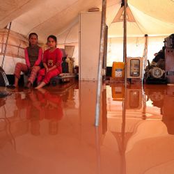 Dos niñas se sientan dentro de una carpa inundada en el campamento inundado  | Foto:Omar Haj Kadour / AFP