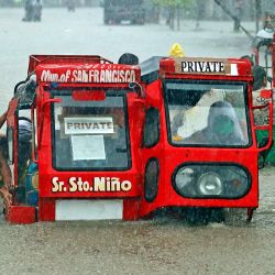 La gente empuja un triciclo medio sumergido a través de una calle inundada debido a las fuertes lluvias causadas por la depresión tropical Vicky en la ciudad de San Francisco, provincia de Agusan del sur en la isla sureña de Mindanao. | Foto:Erwin Mascarinas / AFP