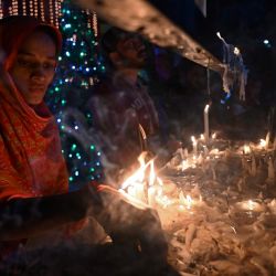 Los devotos cristianos encienden velas fuera de la iglesia de San Antonio antes de las celebraciones navideñas en Lahore. | Foto:Arif Ali / AFP