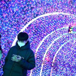 Las personas usan sus teléfonos móviles mientras caminan en un centro comercial en Beijing. | Foto:Noel Celis / AFP