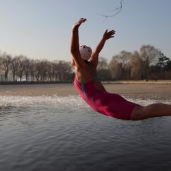 Una mujer salta a un lago parcialmente congelado en un parque en Shenyang, en la provincia de Liaoning, al noreste de China. | Foto:STR / AFP