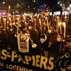 Los manifestantes sostienen velas durante una manifestación por la regularización de los migrantes con motivo del Día Internacional del Migrante, en París. | Foto:Thomas Coex / AFP