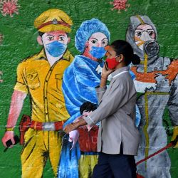 India, Mumbai: una mujer con una mascarilla pasa junto a un grafiti que llama la atención sobre la importancia de usar mascarillas en medio de la pandemia de coronavirus. | Foto:Ashish Vaishnav / SOPA Imágenes vía ZUMA Wire / DPA