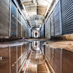 Un palestino pasa por un callejón con charcos de agua en el mercado principal de la ciudad de Gaza, cerrado debido a la pandemia del coronavirus COVID-19. | Foto:Mahmud Hams / AFP