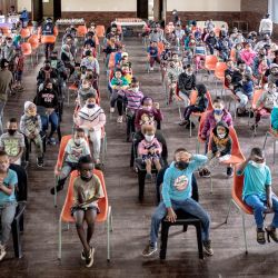 Unos 300 niños se reúnen en la escuela secundaria de Coronationville mientras esperan una distribución de alimentos y productos antes de Navidad, dirigida por la organización benéfica de base Hunger Has No Religion, en Coronationville, Johannesburgo. | Foto:Luca Sola / AFP